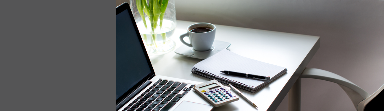 Laptop sitting on desk with calculator and notebook